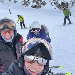 Selbstporträt einer Gruppe von Skifahrern im Schnee, mit verschneiten Bäumen im Hintergrund.