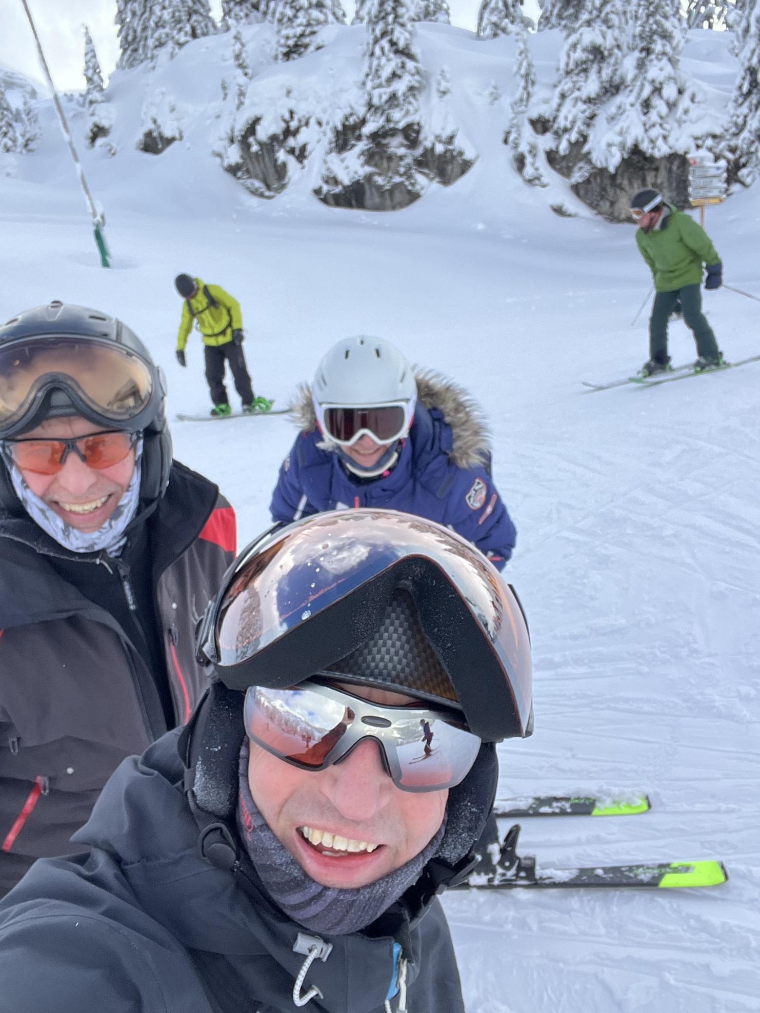 Selbstporträt einer Gruppe von Skifahrern im Schnee, mit verschneiten Bäumen im Hintergrund.