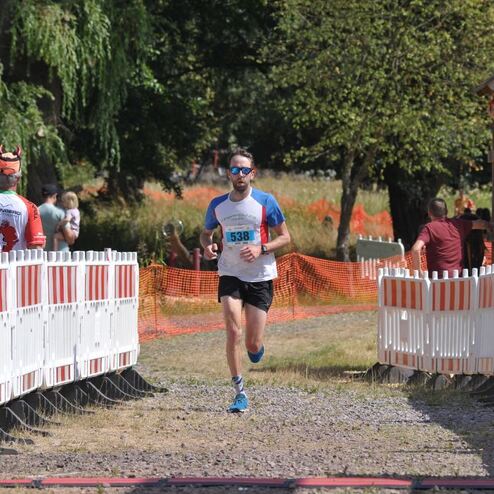 Ein Läufer mit der Startnummer 538 erreicht das Ziel eines Wettbewerbs, umgeben von Zuschauern und Streckenabsperrungen.