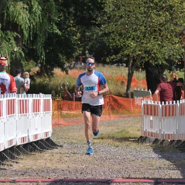 Ein Läufer mit der Startnummer 538 erreicht das Ziel eines Wettbewerbs, umgeben von Zuschauern und Streckenabsperrungen.