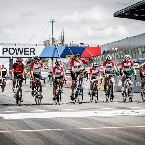 Gruppe von Radfahrern in roten Trikots auf einer Rennstrecke, Überquerung der Ziellinie in einem Wettbewerb.