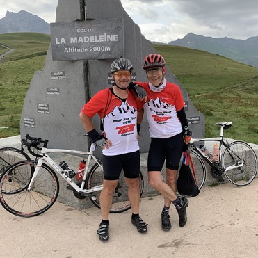 Zwei Radfahrer in sportlicher Kleidung stehen neben ihren Fahrrädern am Col de la Madeleine, einem Bergpass bei 2000 m.