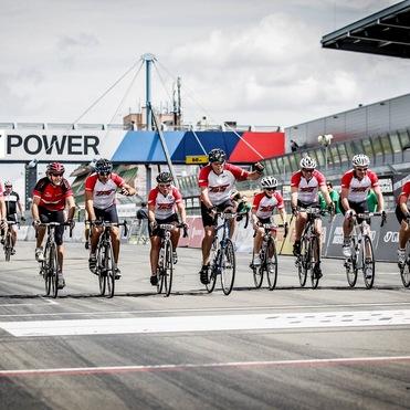 Gruppe von Radfahrern in roten Trikots auf einer Rennstrecke, Überquerung der Ziellinie in einem Wettbewerb.