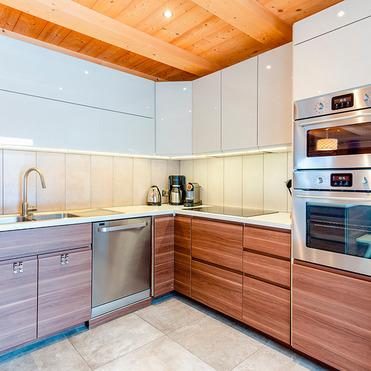 Moderne Küche mit Holzdecken, grauen Oberschränken, braunen Unterschränken und Edelstahl-Geräten.