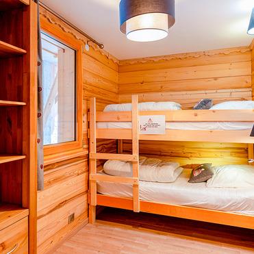 Gemütliches Schlafzimmer mit Hochbett aus Holz, Regalen und Fenster, sanft beleuchtet von Wandleuchten und Deckenlampe.