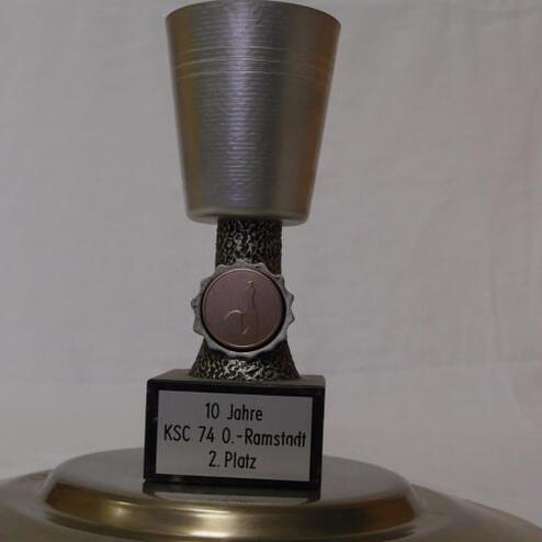 Silberner Pokal mit schwarzem Sockel, beschriftet mit „10 Jahre KSC 74 O.-Ramstadt 2. Platz“.