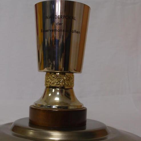 Wanderpokal aus Metall mit goldfarbenem Fuß, graviert mit „WANDERPOKAL der Reservemannschaften“.
