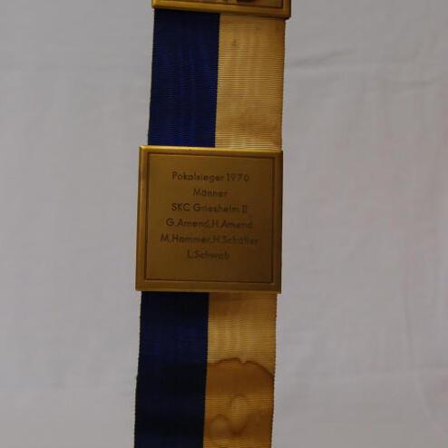 Goldene Medaille mit blau-gelbem Band, graviert mit „Pokalsieger 1970“ und Namen von Spielern.