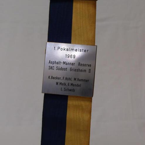 Ehrenmedaille mit blauen und gelben Bändern, graviert mit „1. Pokalmeister 1969“ und Namen der Spieler.