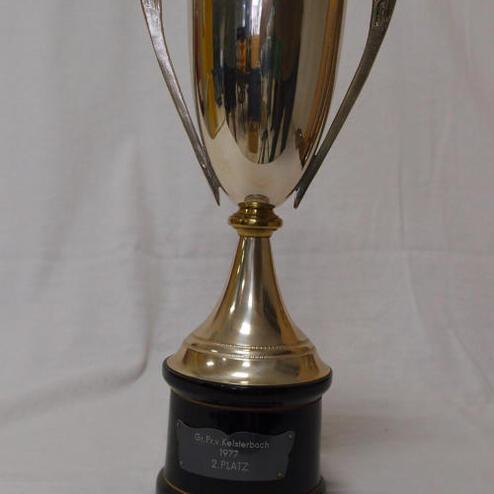 Silberner Pokal auf schwarzem Sockel mit gravierter Plakette „2. PLATZ“ in glänzender Metallfarbe.