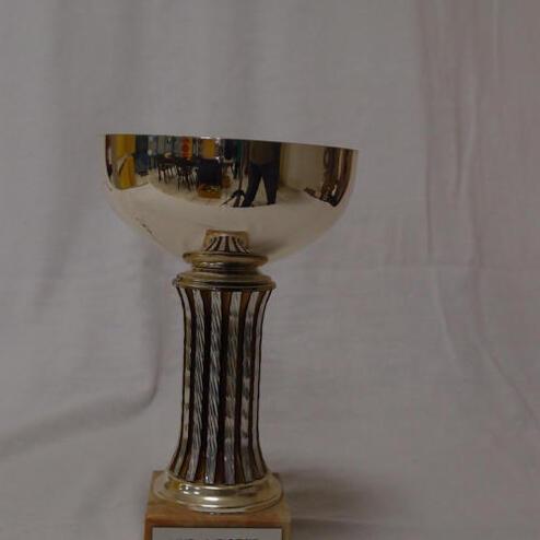 Silberner Pokal mit gravierter Beschriftung „KVD-Meister VMM 1985 SKC -1“ auf einer weißen Unterlage.