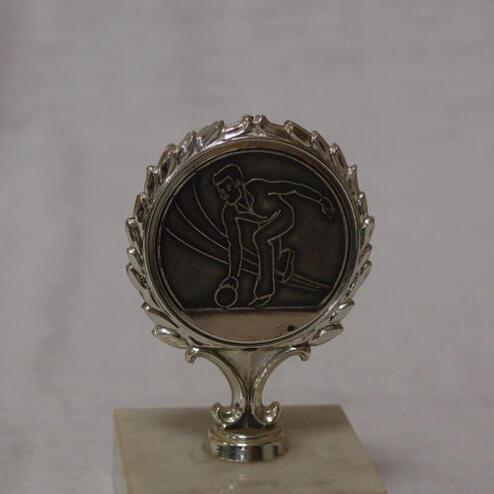 Silberne Medaille auf einem Marmorsockel mit Gravur eines Bowlers in Aktion.