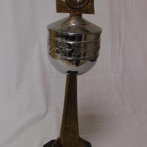 Silberner Pokal mit goldenem Ornament auf einem schwarzen Sockel, beschriftet mit „Sieger KVD Clubmeister“.