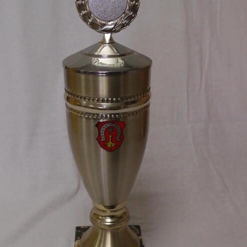 Silberner Pokal auf schwarzem Marmorsockel mit Emblem und gravierter Plakette, auf weißem Hintergrund.