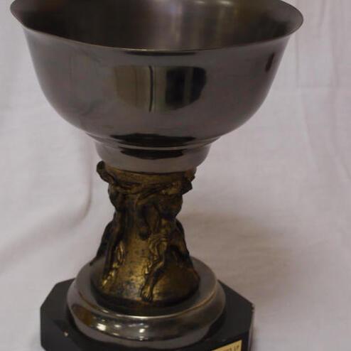 Silberner Pokal mit einem goldenen Sockel, beschriftet mit Siegen von 1992 bis 1994. Hintergrund in weiß.