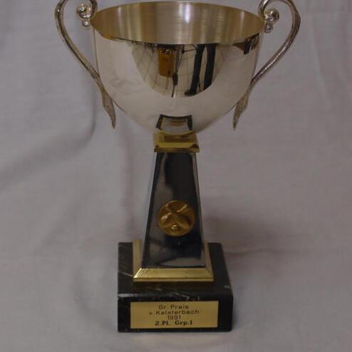 Silberner Pokal mit zwei Griffen auf schwarzem Sockel, graviert mit „2. Pl. Grp. I“.