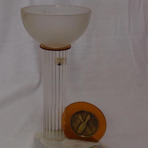 Lerchenförmige Trophäe aus Glas und Marmor mit einer Medaille, graviert, auf einem weißen Hintergrund.