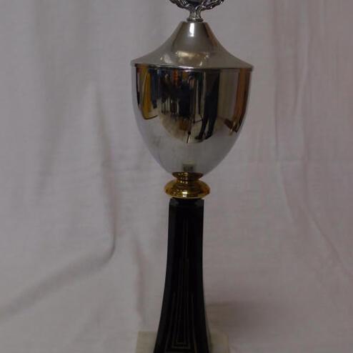 Silberner Pokal auf schwarzem Sockel mit goldener Verzierung und Prägedetails, beschriftet mit "10 Jahre VK 84 DAARMSTADT, 1. Platz 1994".