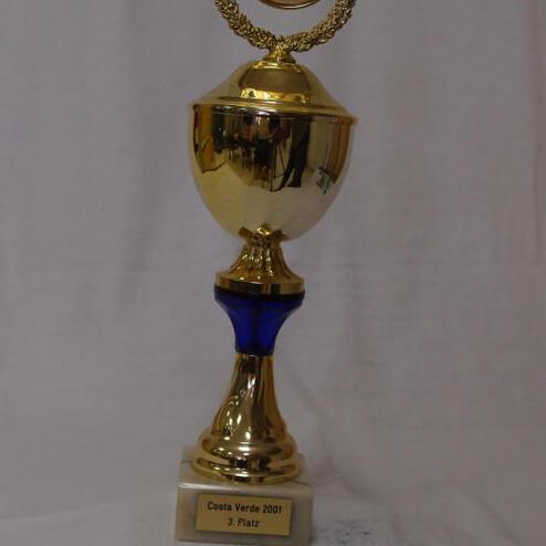 Goldene Trophäe mit blauem Fuß, beschriftet „Costa Verde 2001, 3. Platz“, auf weißem Hintergrund.