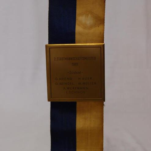Goldene Medaille mit blauer und gelber Schleife, beschriftet mit „2. Stadtmannschaftsmeister 1989“ und Spielernamen.