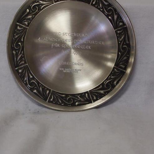 Silberne Plakette mit gravierter Inschrift: „4. Altherrn-Dartturnier für Sportkegler, 1979, 1. Preis“. Ornamental verzierter Rand.