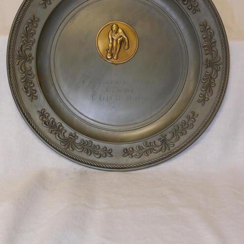 Silberner Pokal mit goldener Plakette, darauf eine Figur und die Gravur „Vereinsmeister 2004, D-Liga II, Platz 1“.