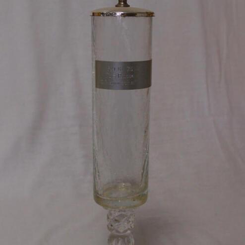 Glas mit massivem Fuß und bronziertem Deckel, darauf eine Medaille, beschriftet mit einem sportlichen Motiv.