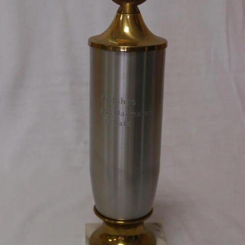 Silberner Pokal mit goldenem Deckel auf marmoriertem Sockel, graviert mit "3. Platz Turnier".