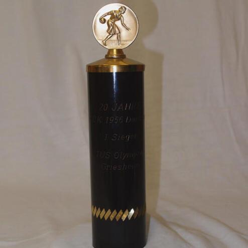 Schwarz-goldener Pokal mit einer Medaille oben, graviert mit „1. Platz, TUS Olympiad Gresheim, 20 Jahre“ und sportlicher Figur.