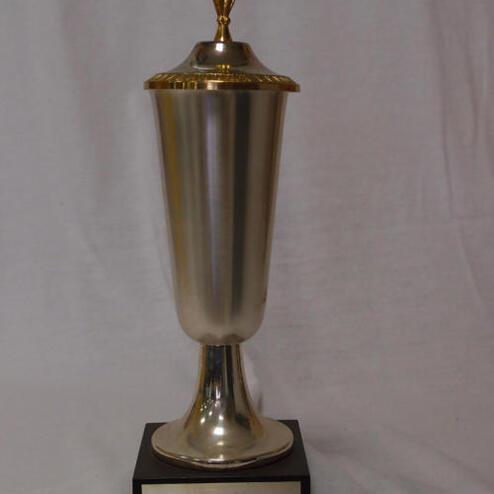 Silberner Pokal mit goldenem Deckel und Blattverzierung auf schwarzem Sockel, beschriftet mit „Gest. v. M. Landau“.