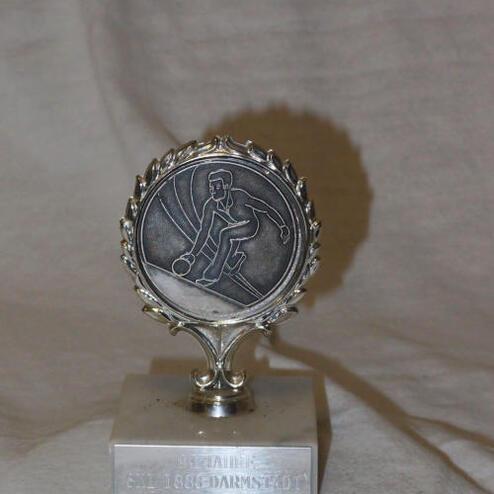 Silberner Pokal mit stilisiertem Spieler und der Aufschrift „1863 Darmstadt“ auf quadratischer Basis.