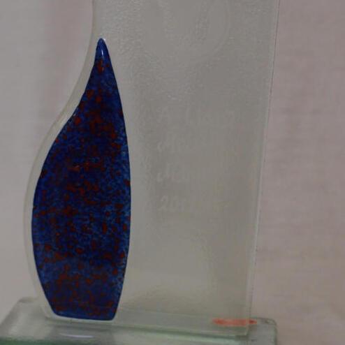 Durchsichtige Glastrophäe mit blauer Füllung und eingravierter Schrift auf einem stabilen Sockel.