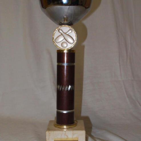 Silberne Pokalschale auf einem braunen Sockel mit einer Gravur und einem Emblem mit Scheren.