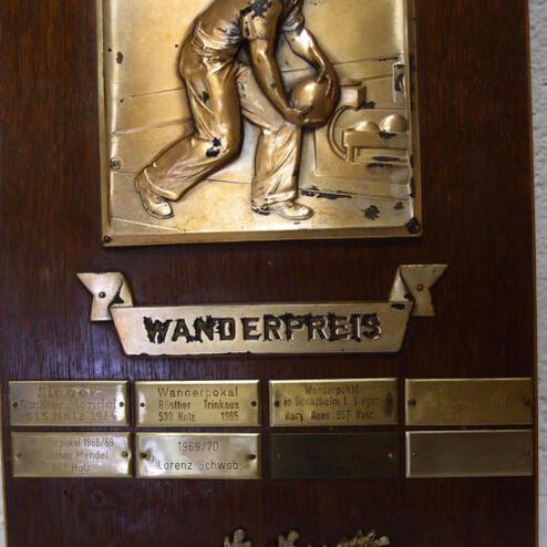 Wandertrophäe aus Holz mit bronzener Platte und Relief eines Bowlingspielers, geschmückt mit entzinnte Plaketten.