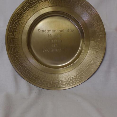 Runde, goldene Medaille mit Gravur „Stadtmannschafts-Meister Herren 1973 SKC Griesheim“ auf hellem Hintergrund.