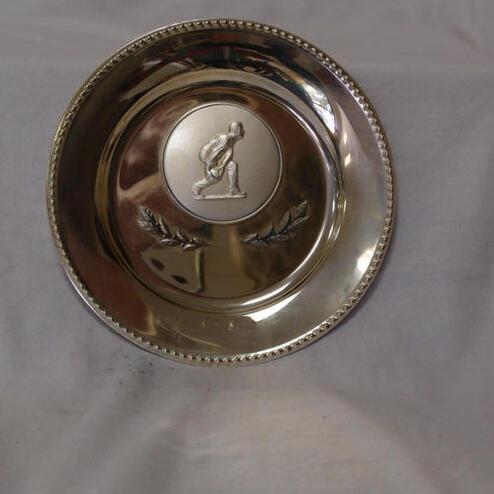 Silberne Medaille mit erhabenem Sportler-Relief und Laubornamenten auf einem weißen Hintergrund.