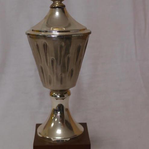 Silberner Pokal auf Holzsockel, beschriftet mit „1984, 25 Jahre SKG Giesheim, 3 Mannschafts Siegertitel“.