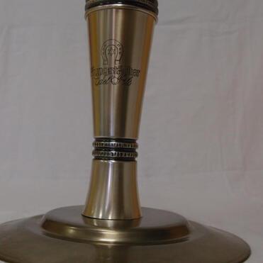 Silberfarbener Pokal mit stilisiertem Deckel auf einem runden Sockel, graviert mit "Meisterschaft".