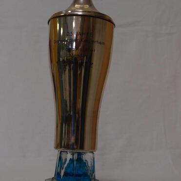 Glänzender Pokal mit blauem Sockel, beschriftet mit "25. Jahr Damenturnier Kellerheim".