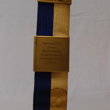 Goldene Medaille mit blau-gelbem Band, graviert mit „Pokalsieger 1970“ und Namen von Spielern.