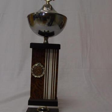 Silberner Pokal mit Emblem oben, auf einer Holzstele mit Inschrift „SSV Raunheim 19. Juni 1983“.