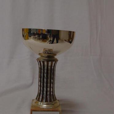 Silberner Pokal mit gravierter Beschriftung „KVD-Meister VMM 1985 SKC -1“ auf einer weißen Unterlage.