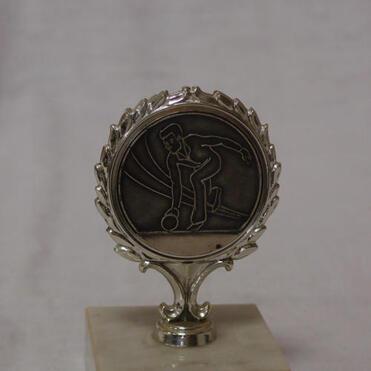 Silberne Medaille auf einem Marmorsockel mit Gravur eines Bowlers in Aktion.