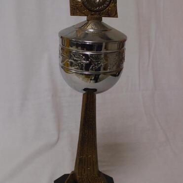 Silberner Pokal mit goldenem Ornament auf einem schwarzen Sockel, beschriftet mit „Sieger KVD Clubmeister“.