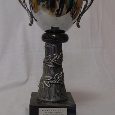 Silberner Wanderpokal mit zwei Griffen auf einem ornamentierten Sockel, beschriftet mit „Wanderpreis der Stadt Breisach“.