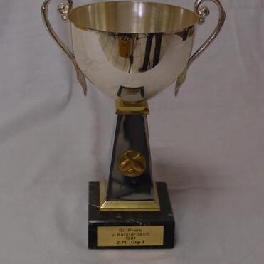 Silberner Pokal mit zwei Griffen auf schwarzem Sockel, graviert mit „2. Pl. Grp. I“.