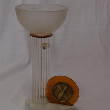 Lerchenförmige Trophäe aus Glas und Marmor mit einer Medaille, graviert, auf einem weißen Hintergrund.