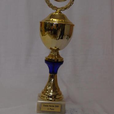 Goldene Trophäe mit blauem Fuß, beschriftet „Costa Verde 2001, 3. Platz“, auf weißem Hintergrund.