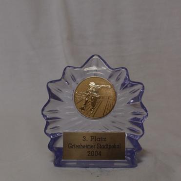 Dreieckiger Pokal mit goldener Medaille und gravierter Plakette: „3. Platz, Griesheimer Stadtpokal 2004“.
