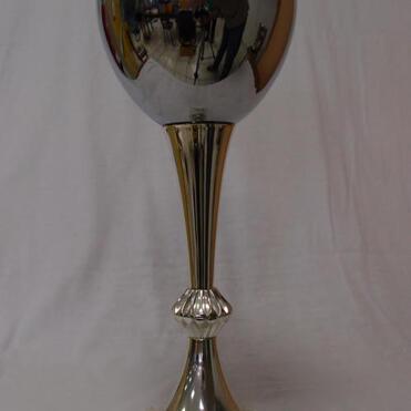 Großer silberner Pokal auf Marmorsockel, mit glatter Oberfläche und dekorativem Standfuß.